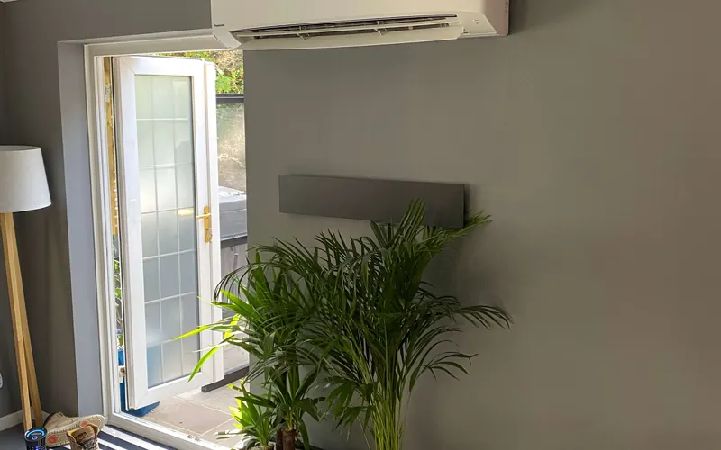 Wall-mounted Panasonic split air conditioning unit installed above a garden door in a residential room